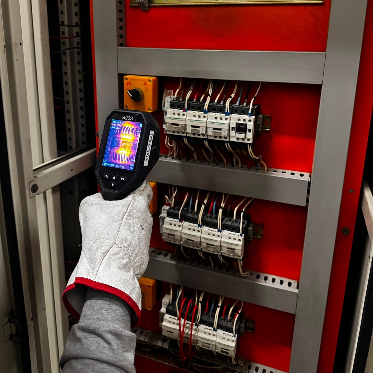 Técnico de Master Job inspeccionando un tablero de contactores con cámara termográfica, con la imagen térmica en pantalla.